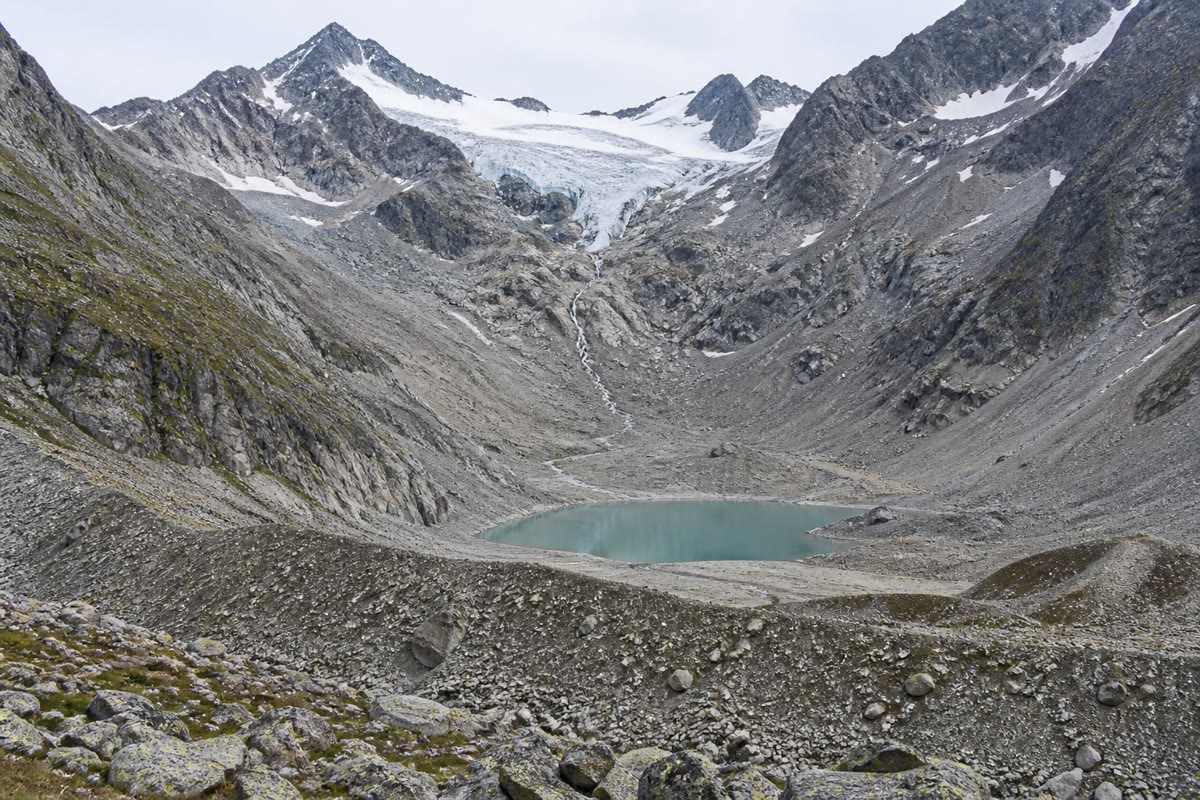 Deux thermomètres. À gauche : un récif blanchi, le squelette blanc du corail apparaissant à travers des tissus qui ont perdu leurs algues. À droite : un glacier de vallée qui a reculé vers l’amont, laissant la roche nue là où se trouvait la glace il y a un siècle.