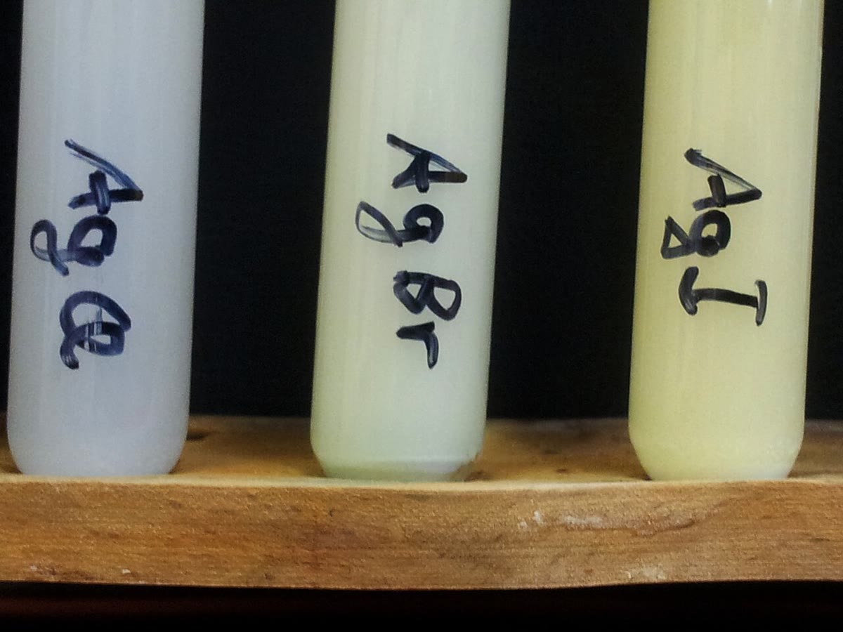 Precipitados de cloreto de prata (branco), brometo de prata (creme) e iodeto de prata (amarelo-claro). Fotografia de Rrausch1974, CC BY-SA 3.0, Wikimedia Commons.