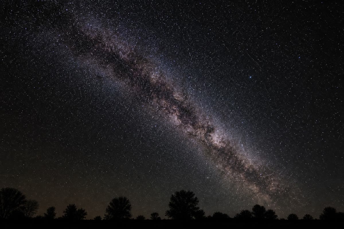 Uma noite realmente escura, longe da cidade: milhares de sóis e a faixa suave da Via Láctea atravessando o céu.