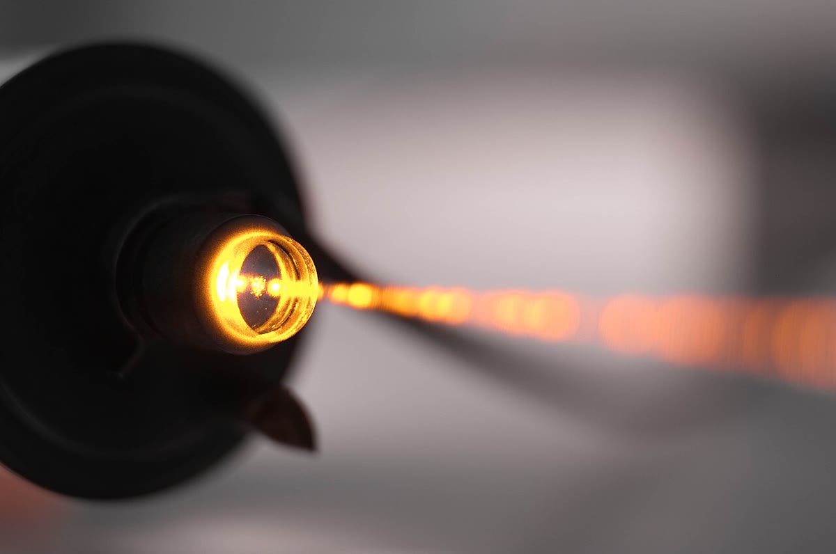 Sebuah tabung laser helium–neon yang memancar pada garis kuningnya pada 594\, nm: cahaya lucutan di dalam tabungnya, dan berkas yang meninggalkannya menembus cermin keluarannya. Foto: Telementor, CC BY 4.0.