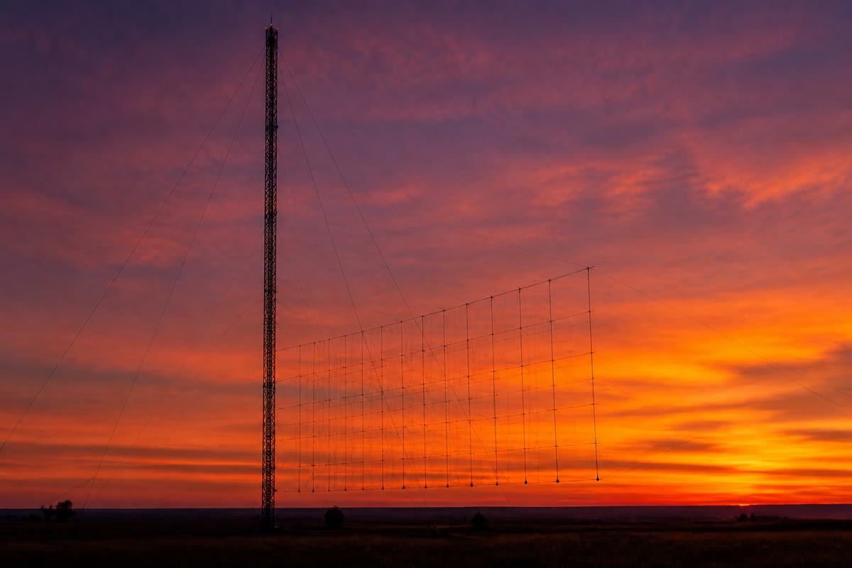 Una estación transmisora de onda corta al anochecer: sus ondas, unos megahercios por debajo de la frecuencia de plasma de la ionosfera, están a punto de reflejarse hacia el suelo a mil kilómetros de distancia.